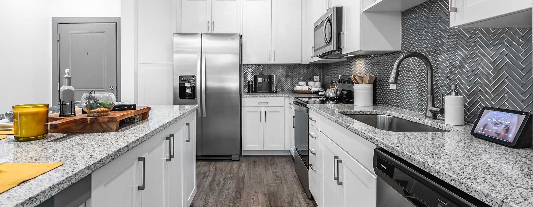 Kitchen space with modern backsplash and countertops, stainless steel appliances, and lots of storage space